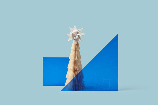 Paper Christmas tree between blue glass panels.