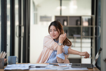 Young businesswoman stretching with hand raised while sitting on a chair in an office.