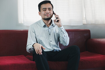 Young Asian man with beard is exciting and smiling when he saw the phone in his hand and knew happy result from it. He raising another hand to cheer it up.
