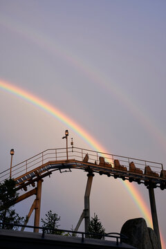Closeup two rainbow in the sky above an amusement park roller coaster