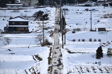 滋賀県里山に積もった雪と真っ直ぐに伸びる田んぼ道