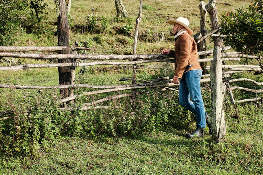 Young cowboy leaning against a wooden fence
