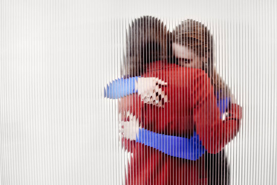 Two persons hugging each other against white background