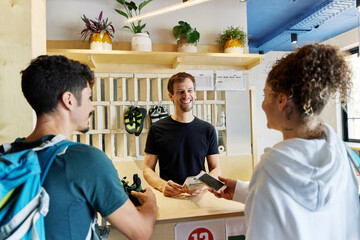 Cheerful couple client paying for service in climbing gym 