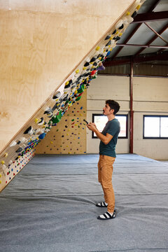 Sportsman using smatrphone near climbing board