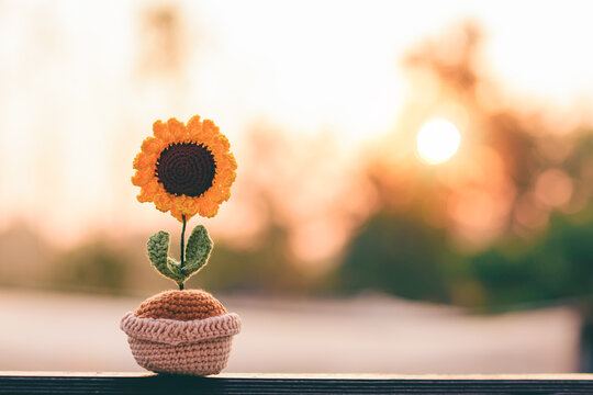Crochet sunflowers in cute little pots. Morning green nature background with sunrise light. Hope of starting something new, Love, encouragement, friendship, willpower, positive image concept.