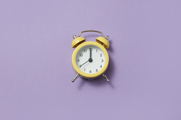 Yellow alarm clock showing twelve o'clock.