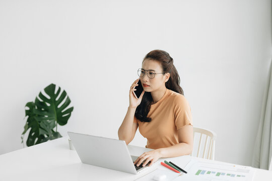 Sad Executive Woman Calling On Smart Phone Sitting At Her Office Desk