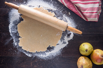 Overhead view of rolling pin with dough and guavas on wooden table