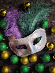 Banner with mardi gras mask, colorful christmas balls and feather on black concrete background....