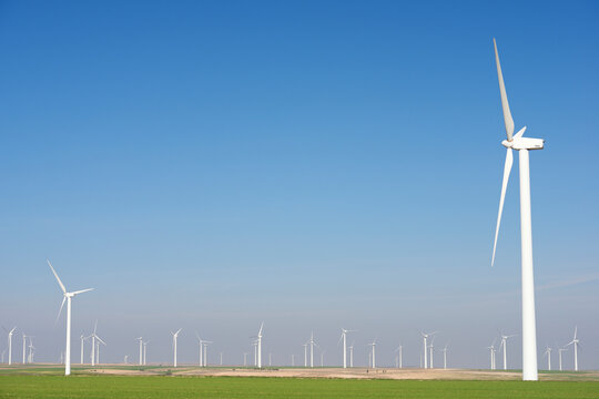 Windmills on field against clear blue sky