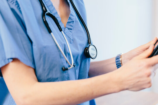 Midsection of female doctor using tablet computer while standing in hospital