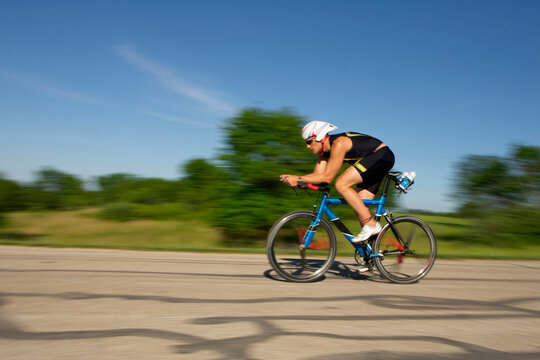 A male athelete training for a triathlon at a lake on a bike.