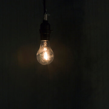 A lit, bare hanging light bulb.