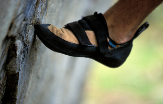 A climber's shoe pressed against a boulder.