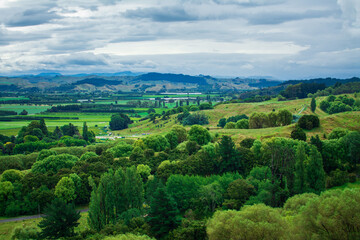 Fototapeta na wymiar Breathtaking New Zealand Landscape with farmland and green rolling hills under cloudy sky. High vantage point. Greys Hill Lookout, Gisborne, North Island, New Zealand