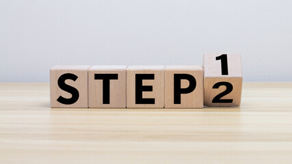 wooden cube block turns step 1 to 2 on a table top for step-by-step operations. There is a...
