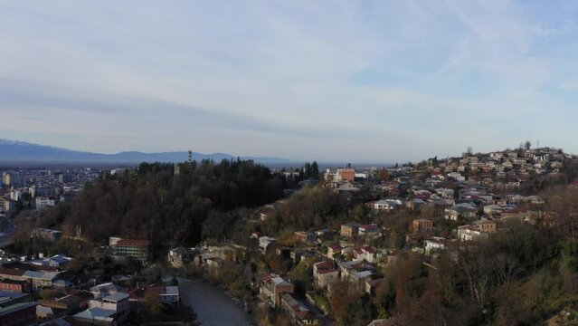 Aerial flying over Kutaisi city with snowy mountains and river