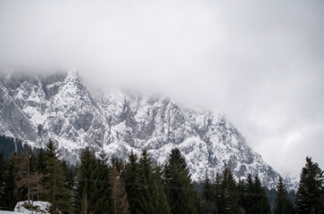 heavy snow clouds hang over the snow-covered mountains and spruce trees