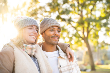 Happy young couple in love smiling and embracing each other, standing outdoors in winter time