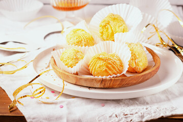 Fried cream puffs filled with chantilly cream- Brighelle typical sweet dish of Umbria for the Carnival, on a wooden plate on a light background.