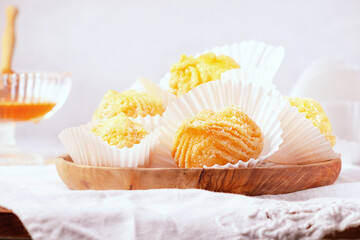 Close-up of fried cream puffs filled with chantilly cream- Brighelle typical sweet dish of Umbria for the Carnival, on a wooden plate on a light background.