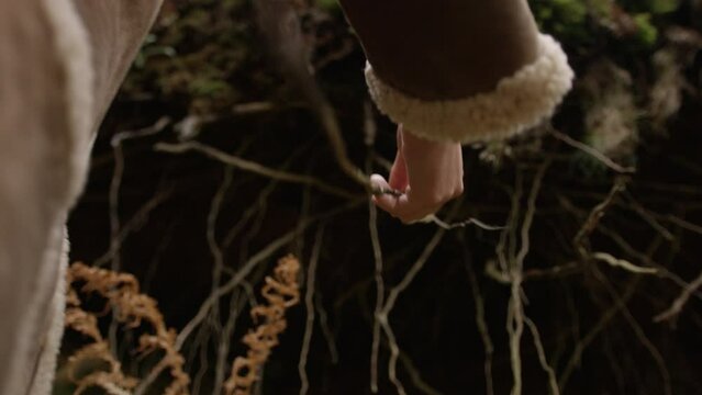 Female Reaching Up To Touch Exposed Roots