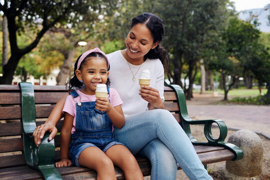 Black family, park and ice cream with a mother and daughter bonding together while sitting on a bench outdoor in nature. Summer, children and garden with a woman and girl enjoying a sweet snack