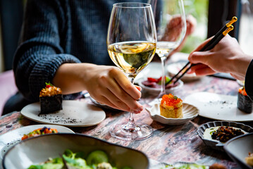woman hand hold glass white wine in restaurant. wine, cheese, meat, vegetables and other appetizers on table