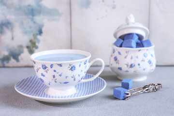 Obraz na płótnie Canvas Blue matcha tea. Blue matcha tea in a white cup. Blue sugar cubes. A natural antioxidant. Light background.