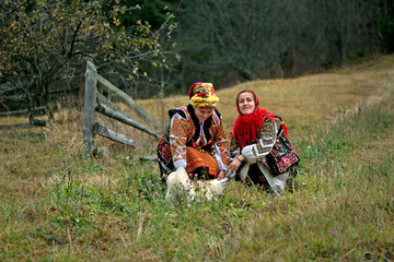 Girls in national hutsul clothes are playing with a dog