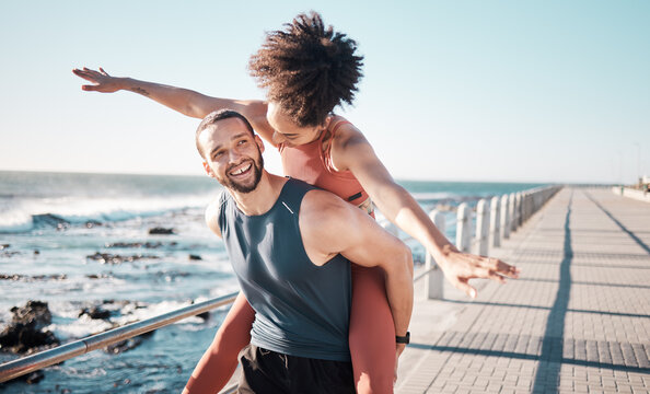 Summer, freedom and couple piggyback by ocean enjoying holiday, vacation and quality time on weekend. Love, dating and black man and woman relax after running, fitness workout and training by beach
