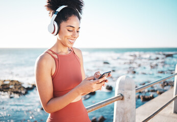 Black woman at beach, headphone and phone with fitness, runner listening to music for sports...