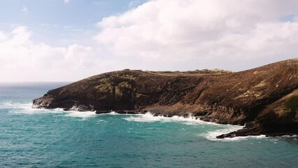Aerial drone approach shot of waves crashing against rocky coastline