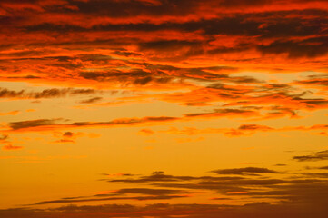 Background image with clouds in extreme colors of a sunset. The sky seems to burn