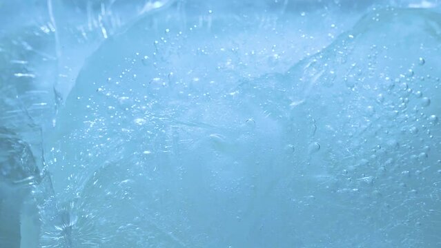 Macro blue broken ice texture background with splashing water surface and ripple