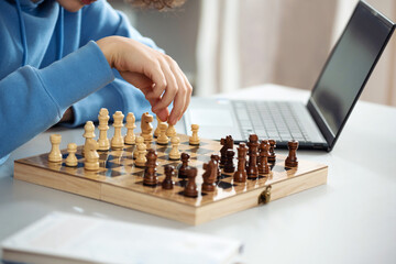 Female teenager play chess with himself. Closeup hand hold pawn. Home hobby, learning to play chess...