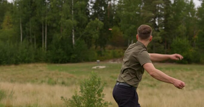 Disc golfer hhrowing a back hand throw to approach basket - Medium shot