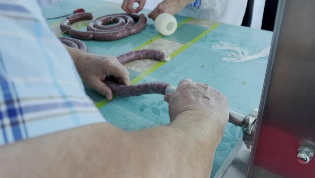 Sausages fill with sausage meat into the animal intestine. Sausage machine on the table makes food. Handheld cam