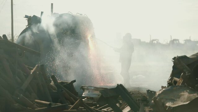 Metal Torcher cutting metal at a scrap yard in slow motion with fire and sparks