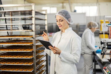 A food factory supervisor is doing quality control of cookies in facility.