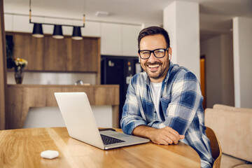 A happy software engineer sits at home and smiles at the camera.