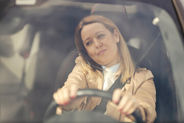 An irresponsible woman is is breaking the law and driving her car while having phone conversation.