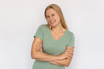 Cheerful young woman crossing arms. Portrait of happy Caucasian female model with fair hair in green T-shirt looking at camera, smiling, proud of herself. Happiness, success concept