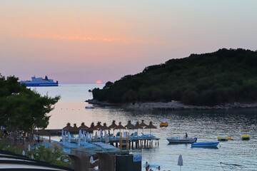 Beach with sun beds and umbrellas at sunset in Ksamil, Albania