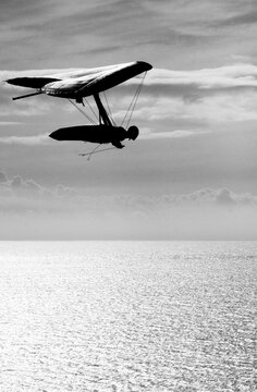 A man soars above the pacific ocean in a hang glider.