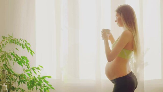 young pregnant woman with uncovered belly a refreshing drink