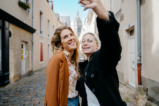 Two female friends taking a selfie in a french touristic town