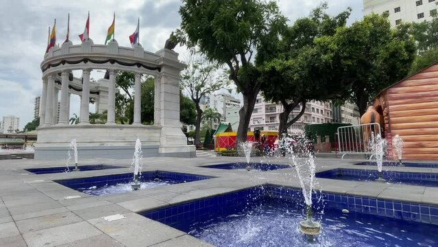 A view of the back of The Rotonda Monument in Malecon Simon Bolivar, Guayaquil, where also some of the sourrounding fountains are located. Tourist passing by.