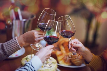 Cheerful friends enjoying home Birthday holiday party. Asian Friends cheering drinking red wine celebrating Christmas or New Year party